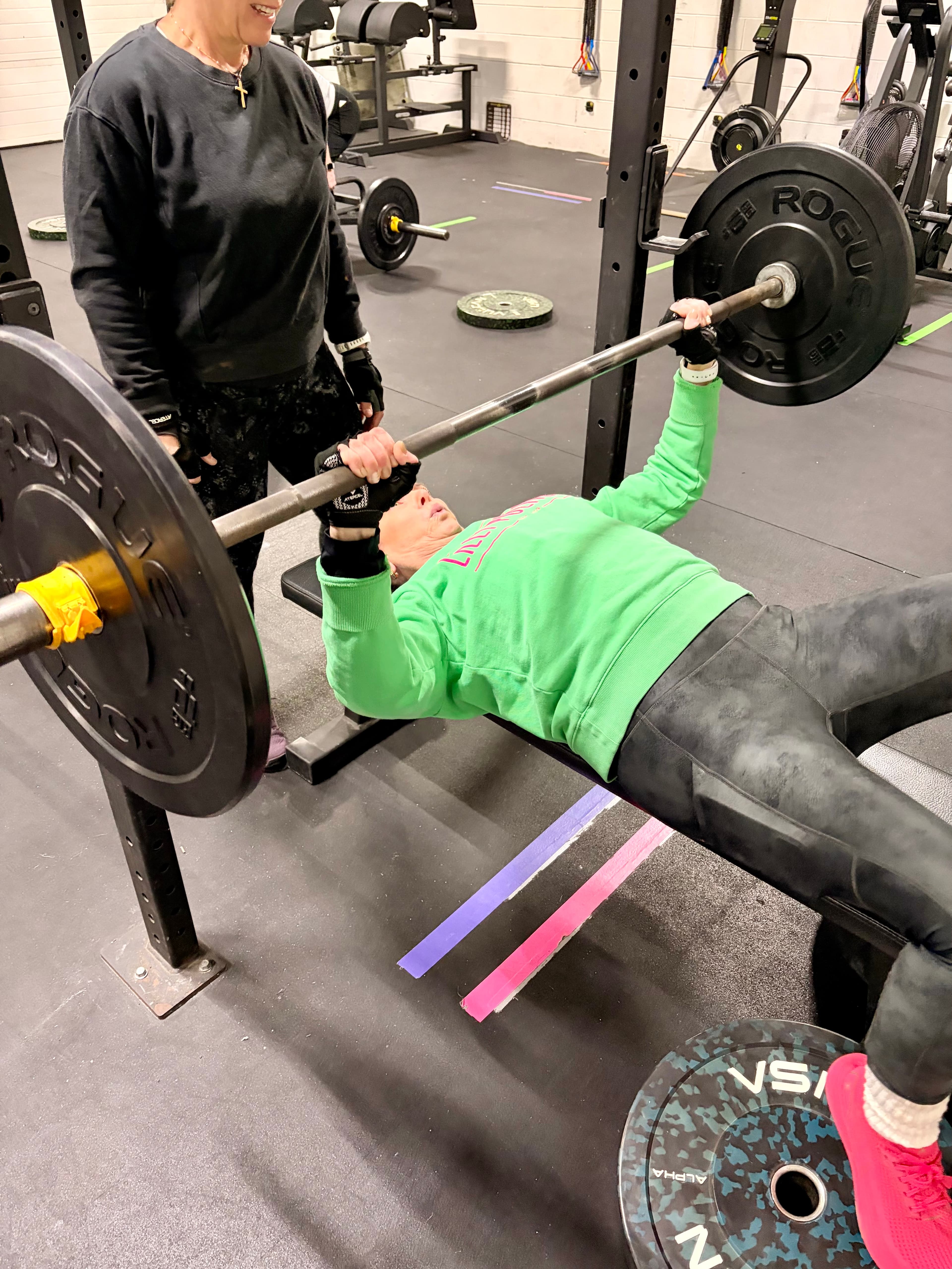 Client bench pressing with a coach