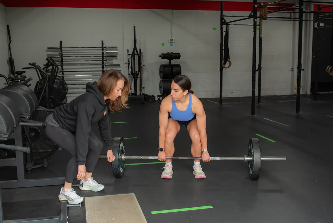 A coach guiding a client through a lift